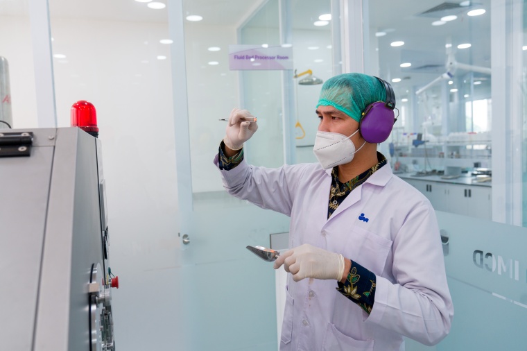 A technician holds a pill for inspection in IMCDs expanded pharmaceuticals...