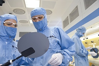 Chemielaboranten begutachten die Oberflächenstruktur eines Siliziumwafers. Im...